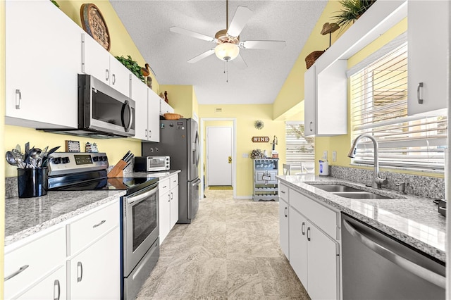 9266 SW 91st Cir, Ocala, FL 34481 - kitchen with stainless steel appliances, a sink, white cabinetry, a ceiling fan, and a textured ceiling