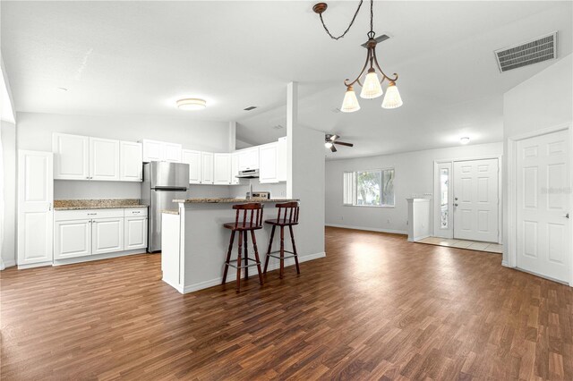 10016 SW 62nd Cir, Ocala, FL 34476 - kitchen with freestanding refrigerator, lofted ceiling, baseboards, wood finished floors, and white cabinets