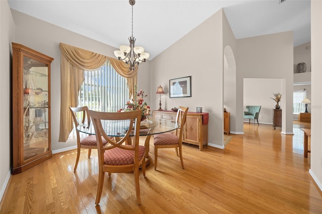 11147 SW 53rd Cir, Ocala, FL 34476 - dining space featuring arched walkways, light wood-style flooring, a chandelier, high vaulted ceiling, and baseboards