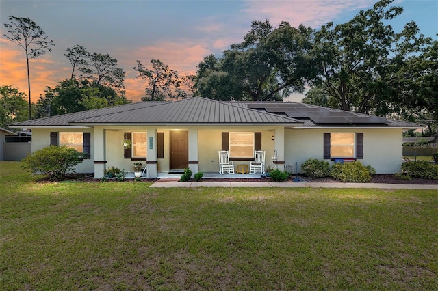 1601 NE 47th Ct, Ocala, FL 34470 - view of front of property featuring covered porch, stucco siding, metal roof, a front lawn, and solar panels