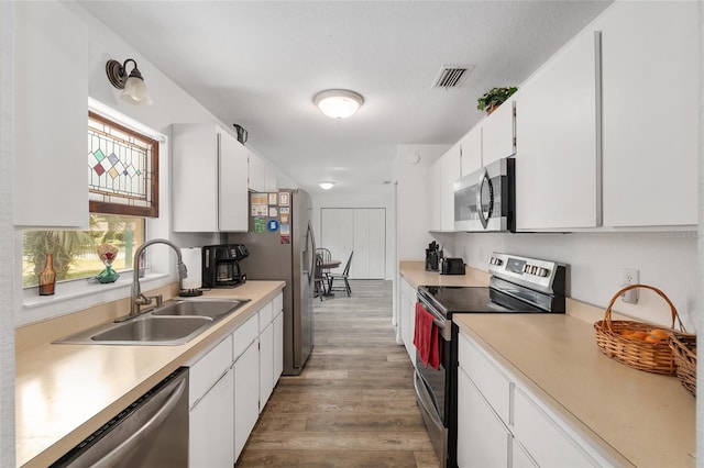1601 NE 47th Ct, Ocala, FL 34470 - kitchen with stainless steel appliances, a sink, light wood finished floors, white cabinetry, and light countertops