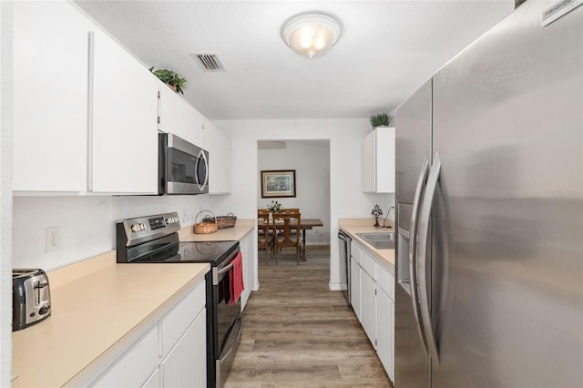 1601 NE 47th Ct, Ocala, FL 34470 - kitchen featuring stainless steel appliances, light countertops, light wood-type flooring, and white cabinetry