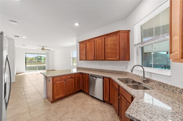 10277 SW 96th Loop, Ocala, FL 34481 - kitchen with appliances with stainless steel finishes, a sink, a peninsula, light stone counters, and brown cabinetry