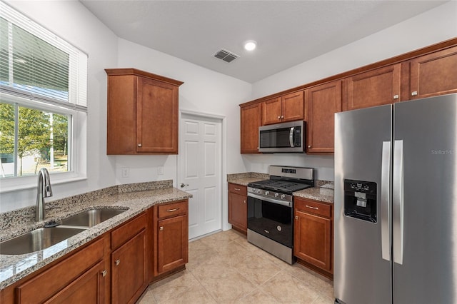 10277 SW 96th Loop, Ocala, FL 34481 - kitchen featuring stainless steel appliances, a sink, light stone countertops, brown cabinets, and light tile patterned floors