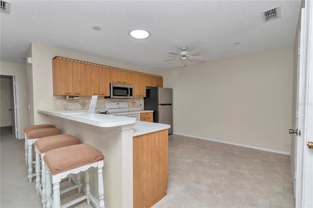 2608 Botello Ave, The Villages, FL 32162 - kitchen with stainless steel appliances, ceiling fan, light countertops, tasteful backsplash, and a textured ceiling