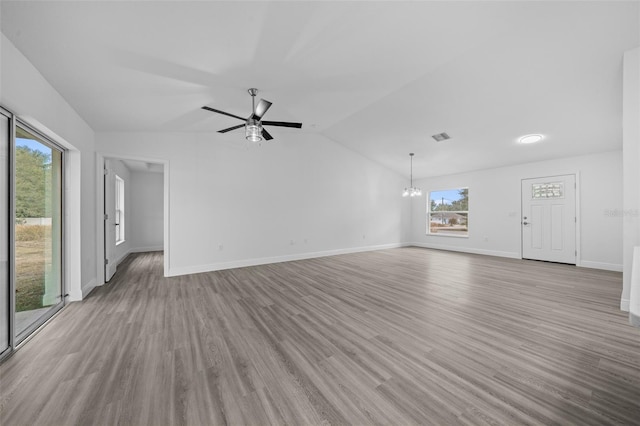 7 Walnut Pl, Ocala, FL 34480 - unfurnished living room featuring vaulted ceiling, light wood-style flooring, baseboards, a chandelier, and a ceiling fan