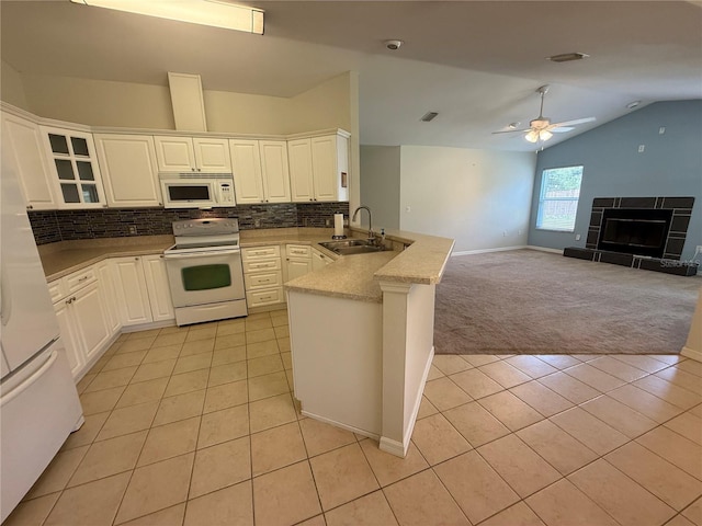 206 SE 8th Ave, Williston, FL 32696 - kitchen with white appliances, a peninsula, light colored carpet, light tile patterned floors, and lofted ceiling