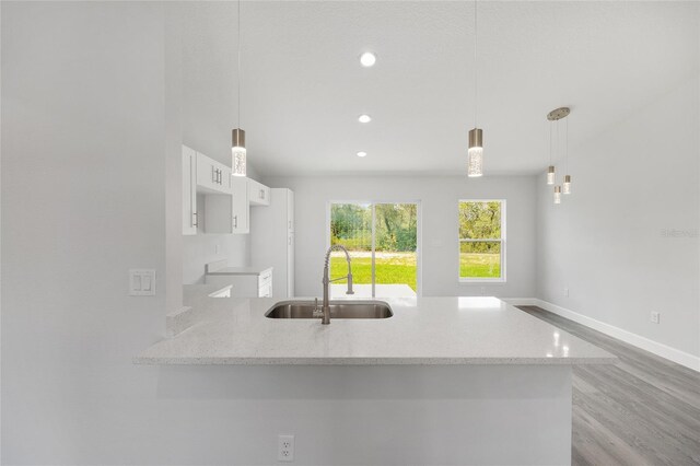 16697 SW 30 Avenue Rd, Ocala, FL 34473 - kitchen featuring a sink, white cabinets, light stone counters, light wood-type flooring, and baseboards