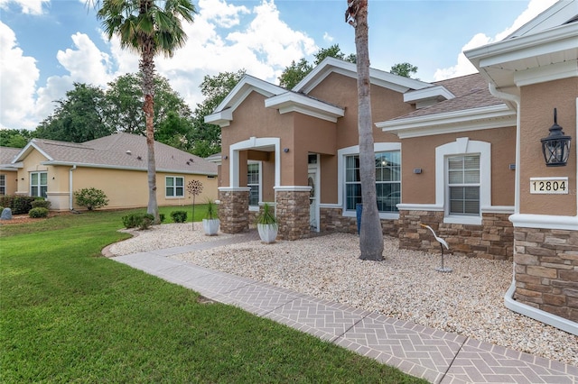 12804 SE 90th Court Rd, Summerfield, FL 34491 - view of front of home with stone siding, a front lawn, stucco siding, and a shingled roof