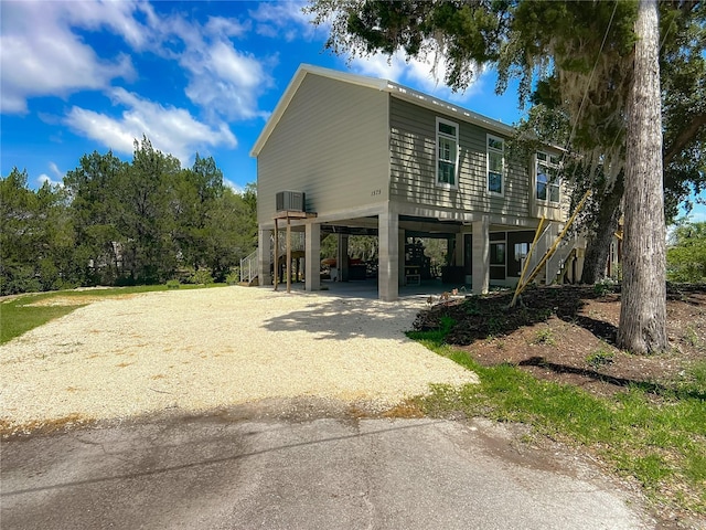1575 S Wallace Pt Unit 23, Crystal River, FL 34429 - view of side of home with stairs, a carport, gravel driveway, and central AC