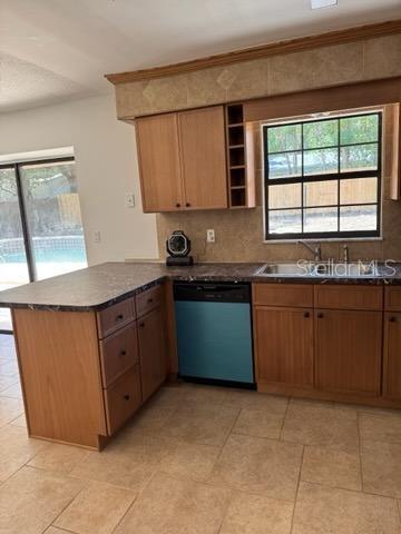 3740 NE 5th St, Ocala, FL 34470 - kitchen with dishwashing machine, a peninsula, a sink, dark countertops, and crown molding