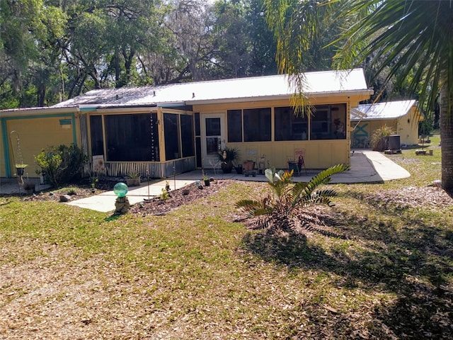 22736 SW 117th St, Dunnellon, FL 34431 - rear view of property featuring a sunroom, metal roof, a yard, and a patio