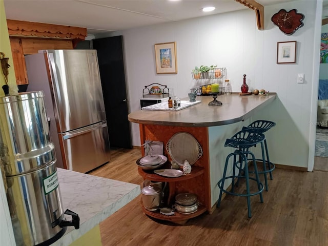 22736 SW 117th St, Dunnellon, FL 34431 - kitchen featuring freestanding refrigerator, a breakfast bar, wood finished floors, and a peninsula