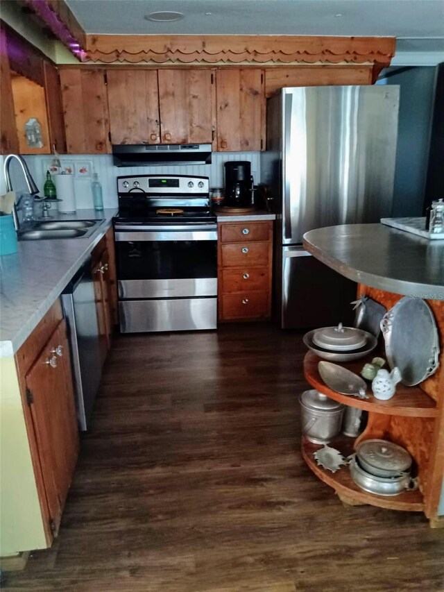 22736 SW 117th St, Dunnellon, FL 34431 - kitchen with stainless steel appliances, under cabinet range hood, brown cabinetry, dark wood-style flooring, and a sink