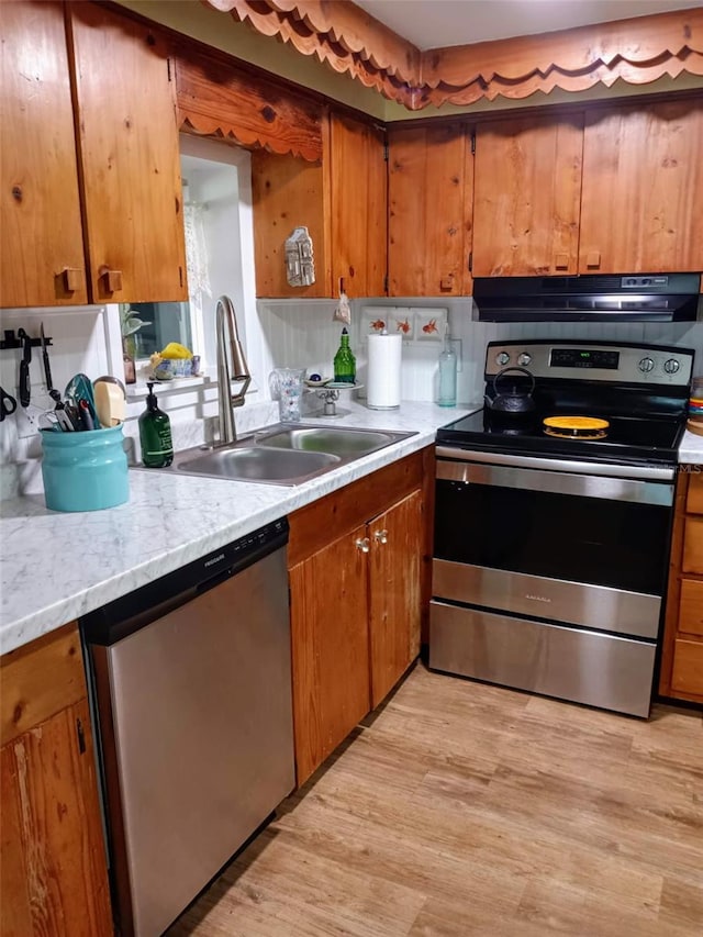 22736 SW 117th St, Dunnellon, FL 34431 - kitchen featuring appliances with stainless steel finishes, light countertops, a sink, light wood finished floors, and brown cabinets