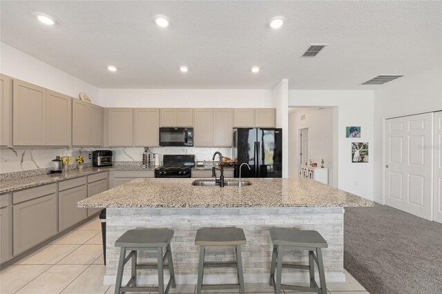 7571 SW 64th Street Rd, Ocala, FL 34474 - kitchen featuring black appliances, a sink, a center island with sink, a breakfast bar, and light stone countertops