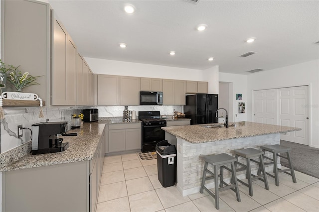 7571 SW 64th Street Rd, Ocala, FL 34474 - kitchen with black appliances, a sink, an island with sink, decorative backsplash, and light tile patterned floors