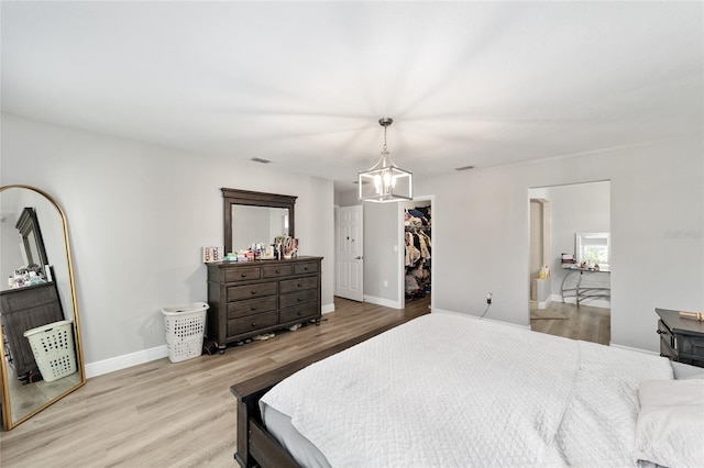11 SE Fir Trail Trak, Ocala, FL 34472 - bedroom featuring a chandelier, light wood-style flooring, a walk in closet, and baseboards