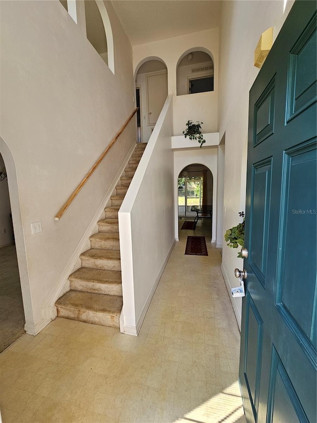 18 Fir Trail Dr, Ocala, FL 34472 - foyer entrance with arched walkways, a towering ceiling, stairway, baseboards, and light floors