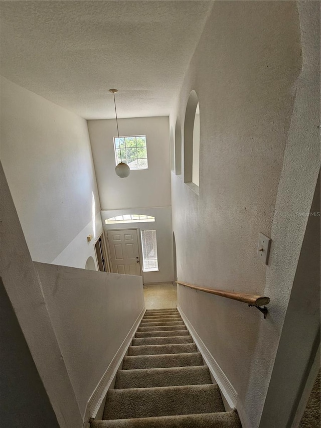 18 Fir Trail Dr, Ocala, FL 34472 - staircase featuring baseboards, a towering ceiling, carpet flooring, and a textured wall