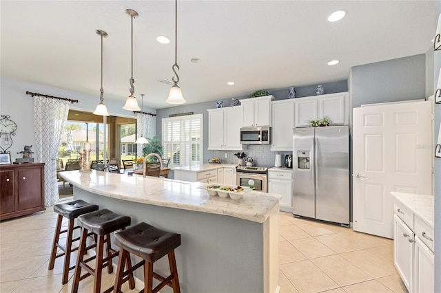 7333 SW 98th Ct, Ocala, FL 34481 - kitchen with stainless steel appliances, light tile patterned floors, a kitchen bar, backsplash, and white cabinetry