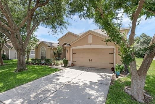 2434 Walnut Heights Rd, Apopka, FL 32703 - ranch-style home with stucco siding, concrete driveway, an attached garage, and a front lawn