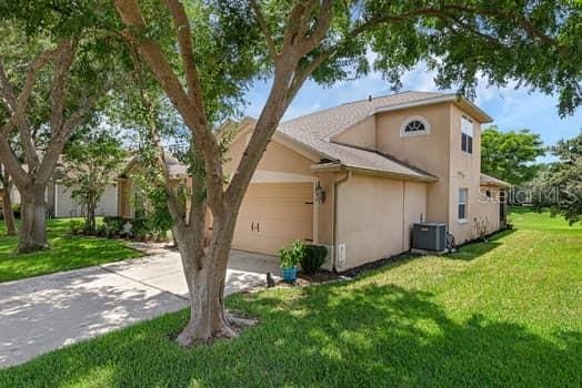 2434 Walnut Heights Rd, Apopka, FL 32703 - view of property exterior with concrete driveway, stucco siding, a garage, a lawn, and central air condition unit