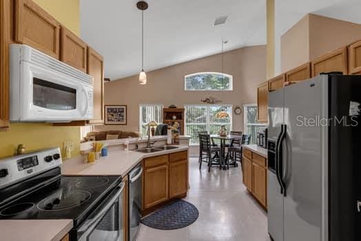 2434 Walnut Heights Rd, Apopka, FL 32703 - kitchen with appliances with stainless steel finishes, vaulted ceiling, a sink, a peninsula, and hanging light fixtures