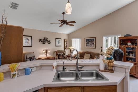 2434 Walnut Heights Rd, Apopka, FL 32703 - kitchen featuring open floor plan, a sink, vaulted ceiling, ceiling fan, and brown cabinets