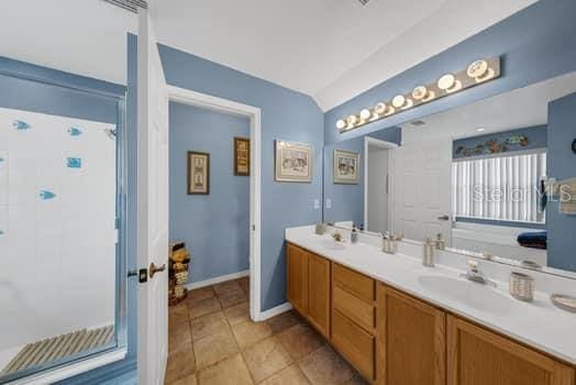 2434 Walnut Heights Rd, Apopka, FL 32703 - bathroom with double vanity, lofted ceiling, tile patterned floors, a shower, and baseboards