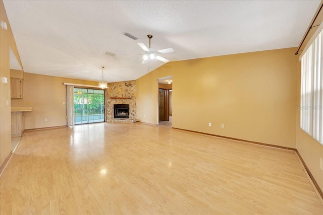 4331 SE 106th Pl, Belleview, FL 34420 - unfurnished living room with a ceiling fan, a stone fireplace, lofted ceiling, light wood-style floors, and baseboards