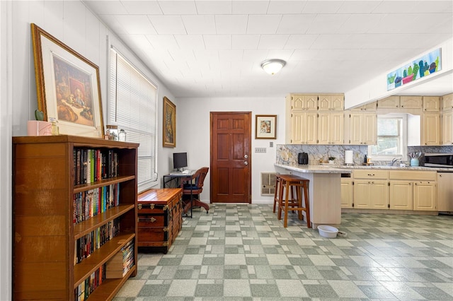 1405 NE 55th St, Ocala, FL 34479 - kitchen featuring stainless steel microwave, cream cabinets, light countertops, and a breakfast bar