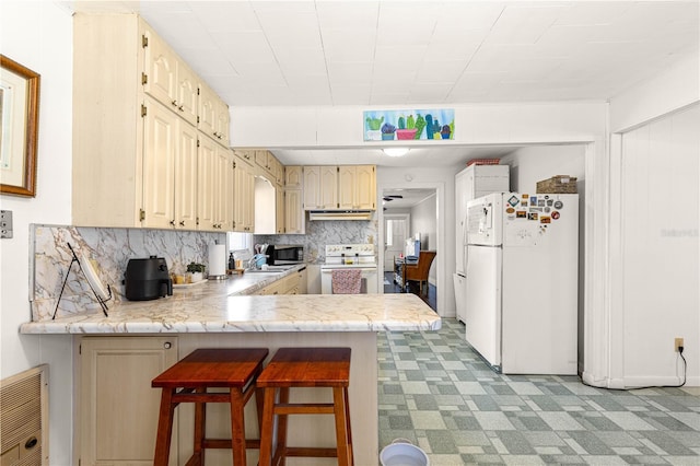 1405 NE 55th St, Ocala, FL 34479 - kitchen featuring white appliances, under cabinet range hood, a peninsula, light countertops, and decorative backsplash