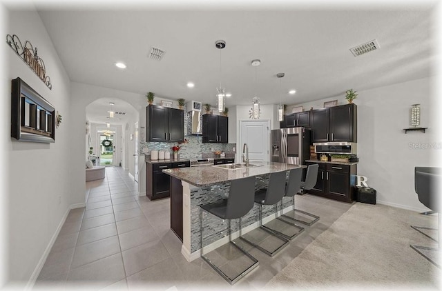 96 Hickory Crse, Ocala, FL 34472 - kitchen with arched walkways, wall chimney range hood, decorative backsplash, a breakfast bar area, and light tile patterned floors