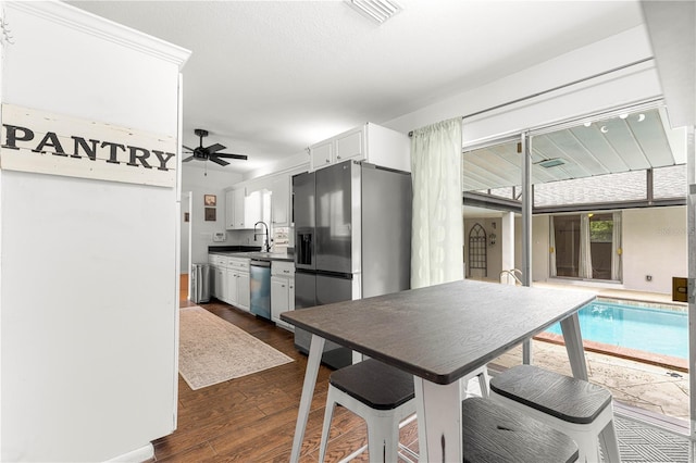 2475 SW 7th Ave, Ocala, FL 34471 - kitchen with appliances with stainless steel finishes, a sink, white cabinets, a ceiling fan, and dark wood-style floors