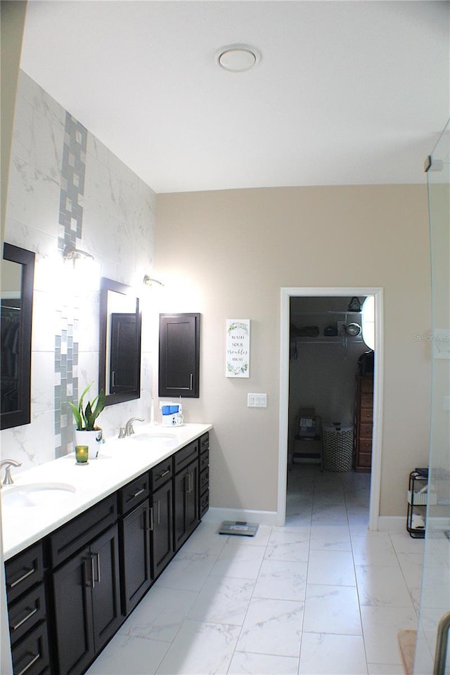 5306 W Comstock Pl, Beverly Hills, FL 34465 - bathroom with double vanity, baseboards, marble finish flooring, tile walls, and a walk in closet