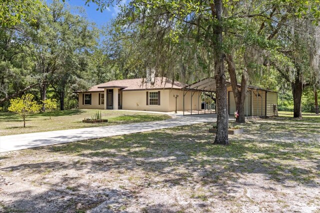 14131 SE 86th Ter, Inglis, FL 34449 - view of front facade with concrete driveway, a carport, a front yard, and stucco siding