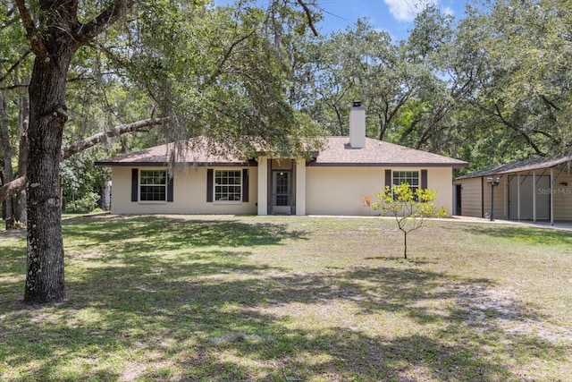 14131 SE 86th Ter, Inglis, FL 34449 - view of front facade with a chimney, a front lawn, and stucco siding
