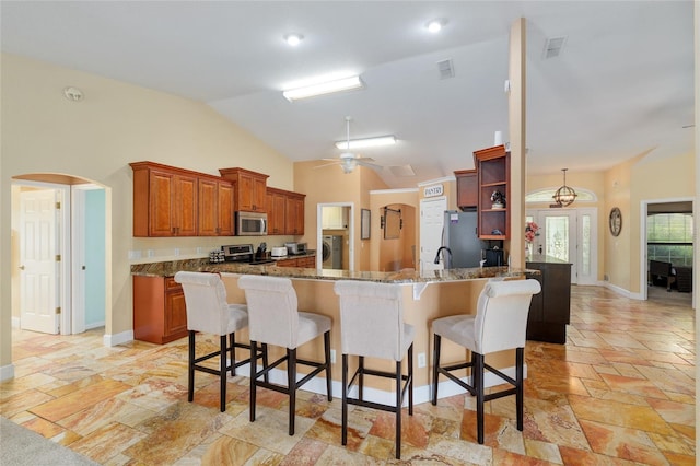 12495 SW 66th St, Ocala, FL 34481 - kitchen featuring appliances with stainless steel finishes, a peninsula, arched walkways, vaulted ceiling, and a kitchen bar