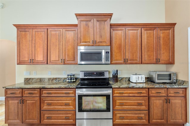 12495 SW 66th St, Ocala, FL 34481 - kitchen with appliances with stainless steel finishes, dark stone countertops, and brown cabinetry