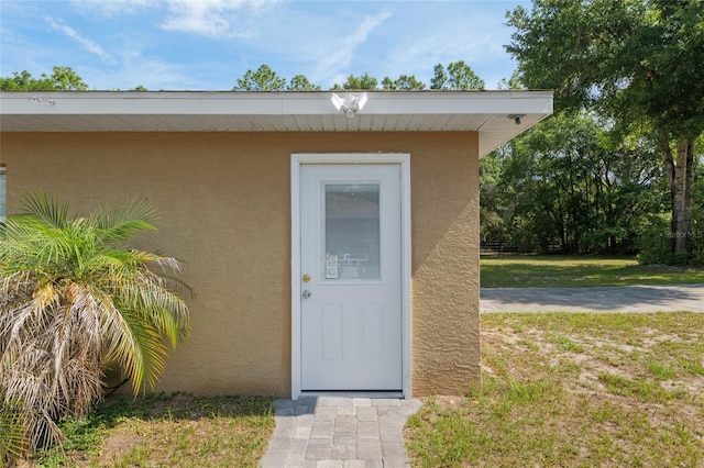 12495 SW 66th St, Ocala, FL 34481 - view of exterior entry featuring stucco siding and a yard