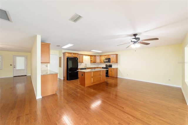 8745 SW 92nd St Unit B, Ocala, FL 34481 - kitchen with black appliances, backsplash, a kitchen island, and light wood finished floors
