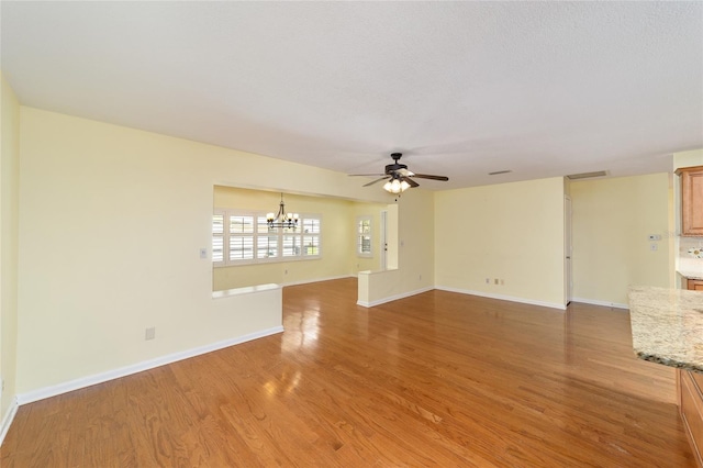 8745 SW 92nd St Unit B, Ocala, FL 34481 - unfurnished living room featuring a chandelier, a ceiling fan, light wood-style flooring, and baseboards