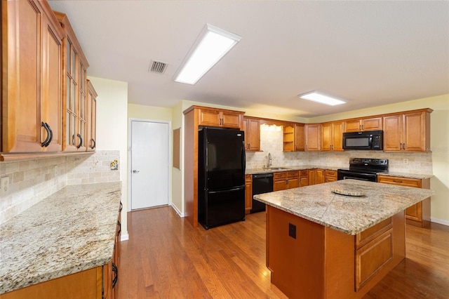 8745 SW 92nd St Unit B, Ocala, FL 34481 - kitchen with black appliances, a sink, backsplash, light stone counters, and brown cabinetry