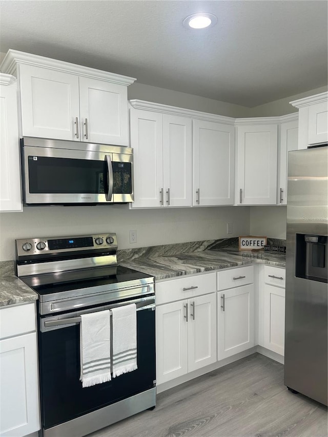960 NW Redwood Dr, Dunnellon, FL 34431 - kitchen with appliances with stainless steel finishes, white cabinets, light wood-style flooring, recessed lighting, and stone countertops