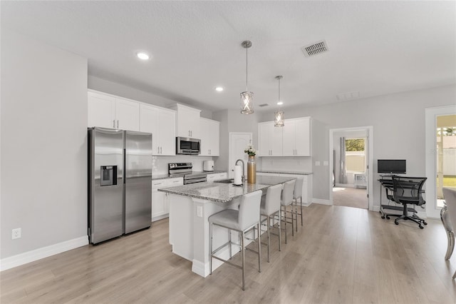 14055 SW 30th Terrace Rd, Ocala, FL 34473 - kitchen featuring stainless steel appliances, a sink, a kitchen bar, an island with sink, and light wood finished floors