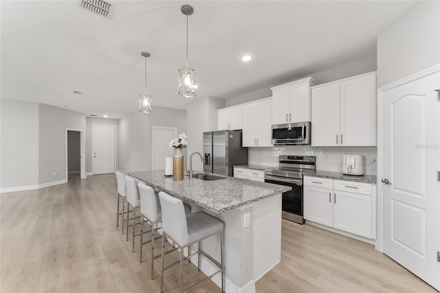 14055 SW 30th Terrace Rd, Ocala, FL 34473 - kitchen featuring stainless steel appliances, a sink, light wood-type flooring, a kitchen island with sink, and backsplash