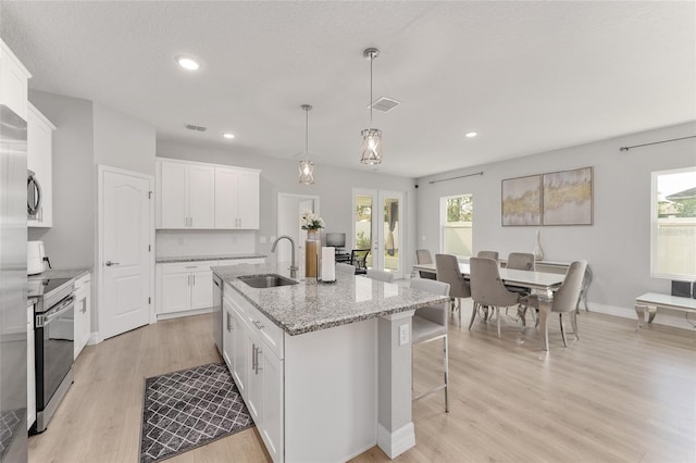 14055 SW 30th Terrace Rd, Ocala, FL 34473 - kitchen with a sink, electric range, a breakfast bar, light wood finished floors, and an island with sink