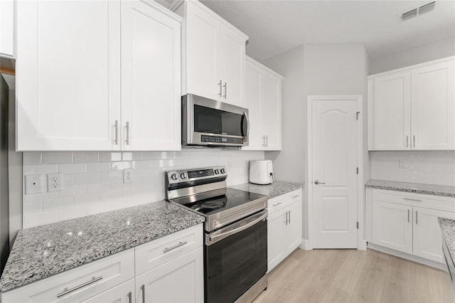 14055 SW 30th Terrace Rd, Ocala, FL 34473 - kitchen featuring appliances with stainless steel finishes, light wood finished floors, white cabinetry, decorative backsplash, and light stone counters