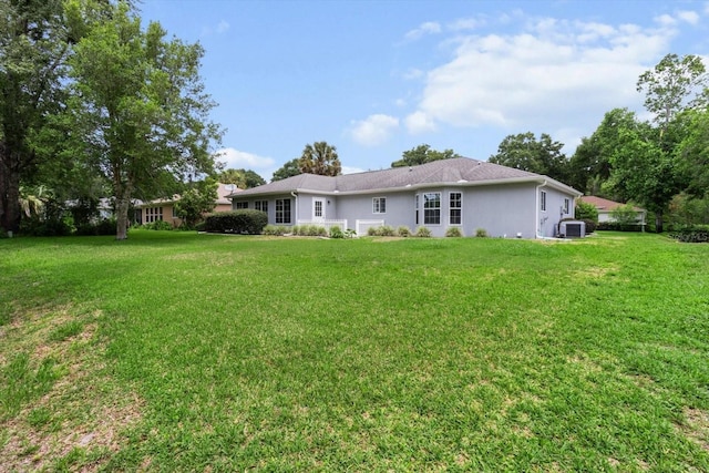14481 SW 112th Cir, Dunnellon, FL 34432 - rear view of house with central AC unit, a yard, and stucco siding